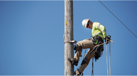 A lineman climbing a pole and blue sky behind