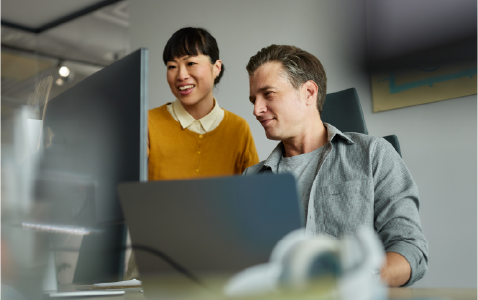 two people smiling and looking at a computer